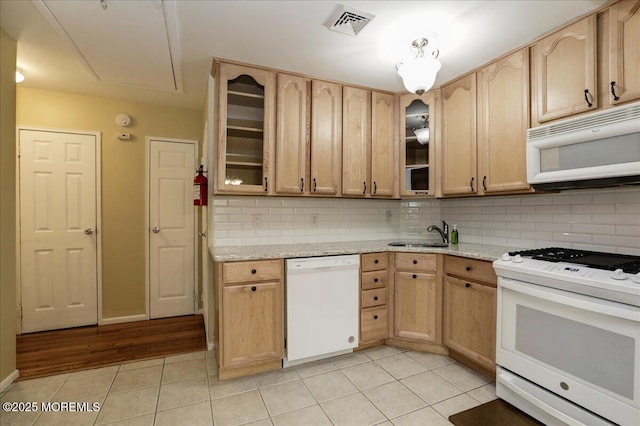 kitchen with light brown cabinetry, white appliances, light tile patterned floors, and backsplash