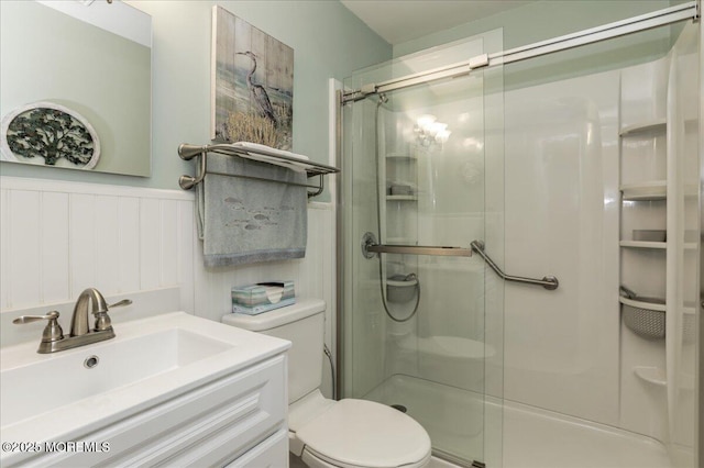 bathroom featuring vanity, toilet, and a shower with shower door