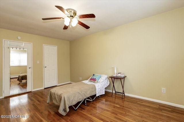 bedroom with hardwood / wood-style floors, ceiling fan, and a baseboard heating unit