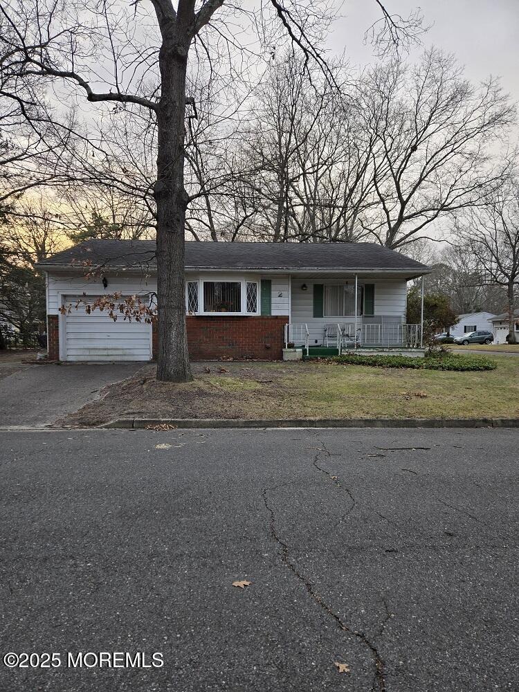 view of front of home with covered porch, a front yard, and a garage