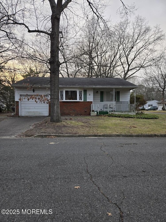 view of front of home with covered porch, a front yard, and a garage