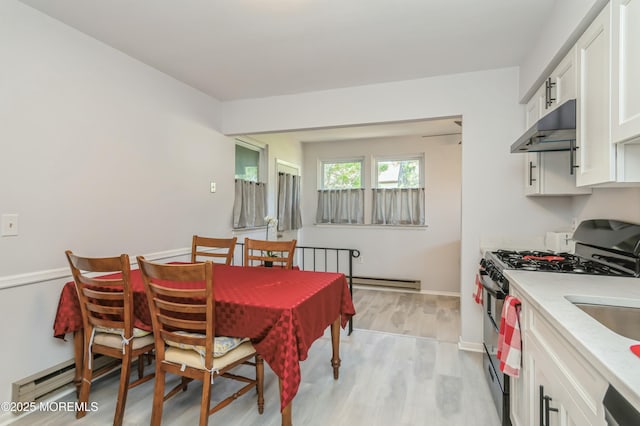 dining space with light hardwood / wood-style flooring and a baseboard heating unit