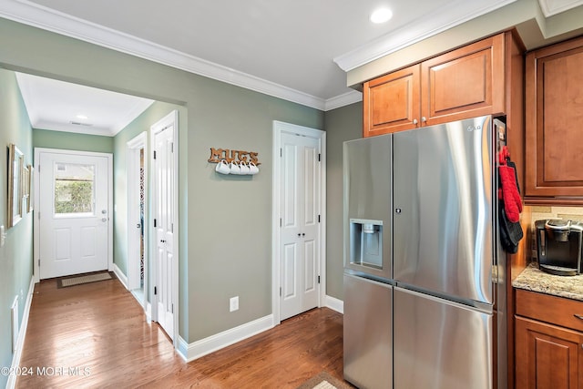 kitchen with crown molding, stainless steel fridge, light stone countertops, and dark wood-type flooring