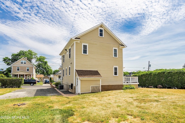 view of side of property featuring cooling unit and a lawn