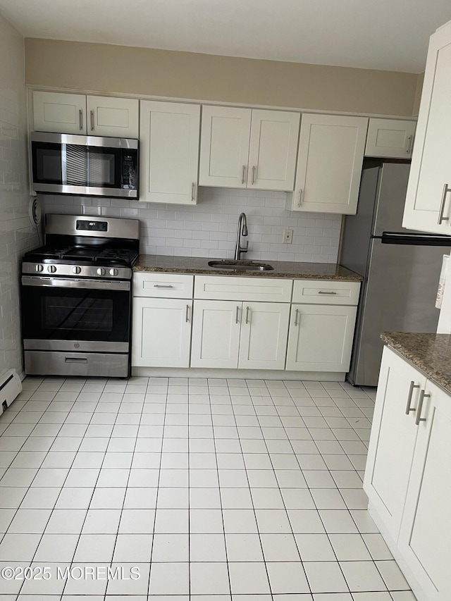 kitchen with appliances with stainless steel finishes, white cabinetry, sink, dark stone countertops, and decorative backsplash