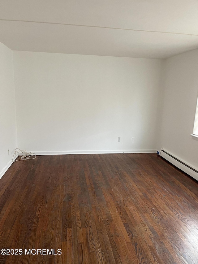 unfurnished room featuring a baseboard heating unit and dark hardwood / wood-style flooring