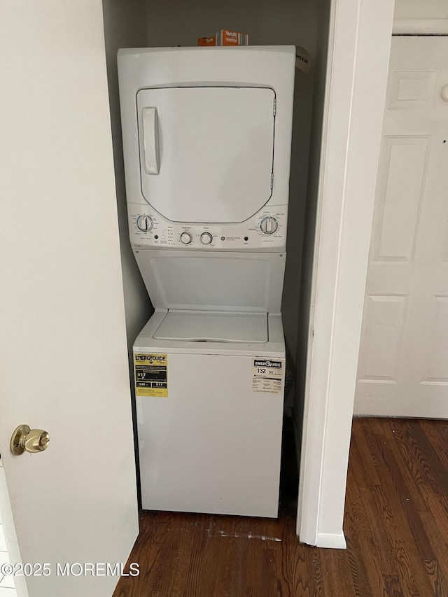 clothes washing area with dark wood-type flooring and stacked washer and clothes dryer