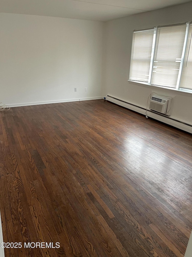 spare room with baseboard heating and dark hardwood / wood-style floors