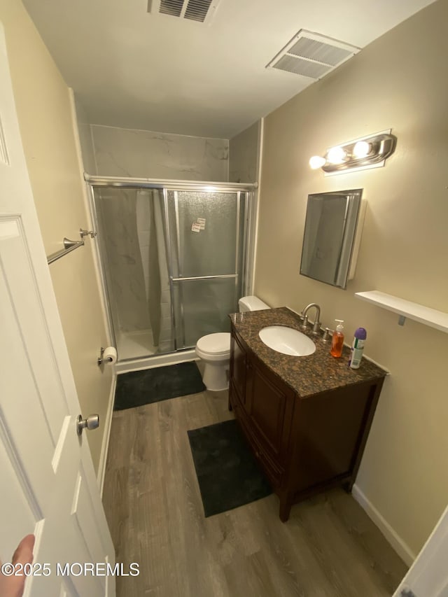 bathroom featuring vanity, toilet, an enclosed shower, and wood-type flooring