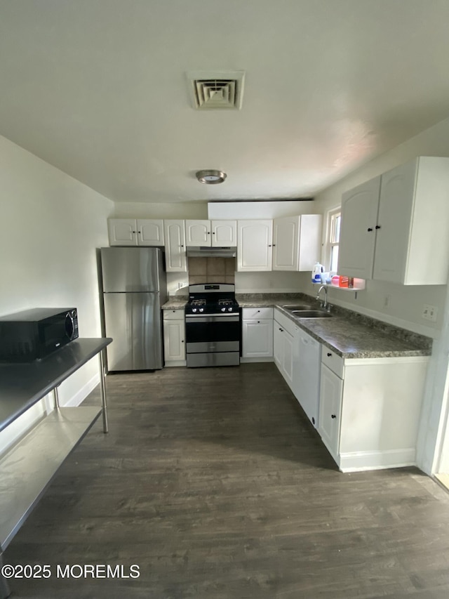 kitchen with white cabinets, appliances with stainless steel finishes, dark hardwood / wood-style flooring, and sink