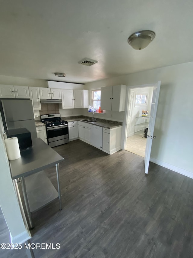 kitchen with dark hardwood / wood-style flooring, white cabinetry, stainless steel range, and sink