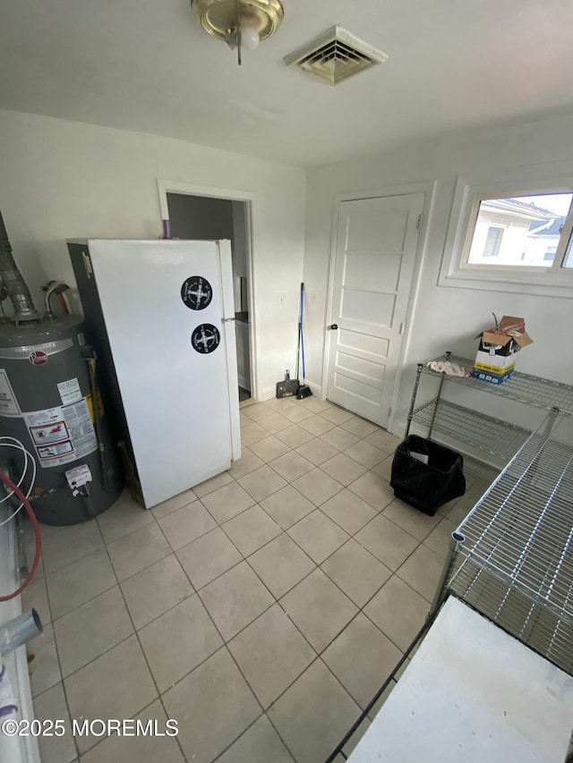 kitchen with white cabinets, water heater, refrigerator, and light tile patterned flooring