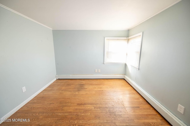 spare room featuring ornamental molding, baseboard heating, and light hardwood / wood-style flooring