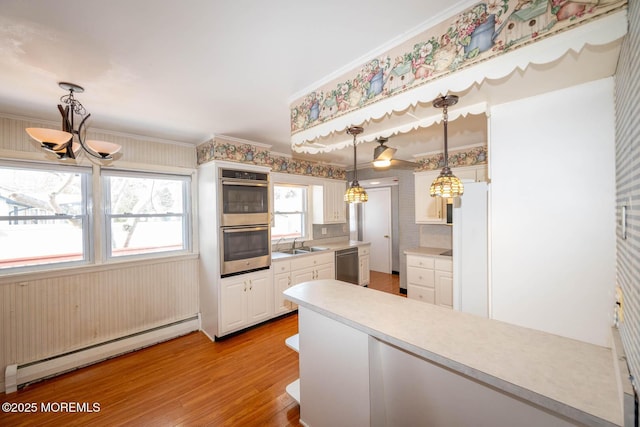 kitchen featuring decorative light fixtures, light hardwood / wood-style flooring, a baseboard radiator, appliances with stainless steel finishes, and ornamental molding