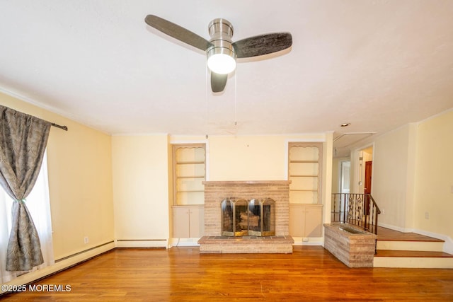 unfurnished living room with a fireplace, built in shelves, wood-type flooring, and ceiling fan