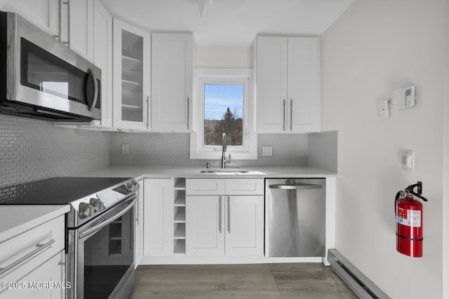 kitchen featuring appliances with stainless steel finishes, white cabinetry, baseboard heating, and sink