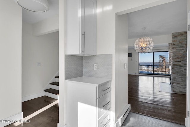 interior space with decorative backsplash, dark hardwood / wood-style flooring, a baseboard radiator, white cabinets, and a chandelier