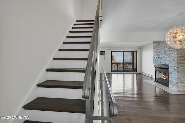 stairs with a fireplace, hardwood / wood-style floors, and a baseboard radiator