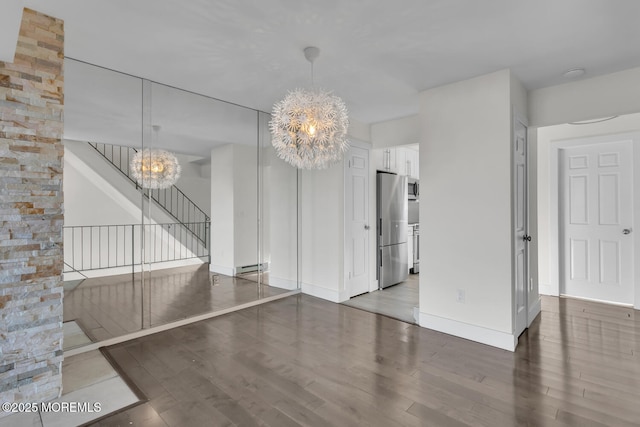 spare room featuring hardwood / wood-style flooring, a baseboard radiator, and an inviting chandelier