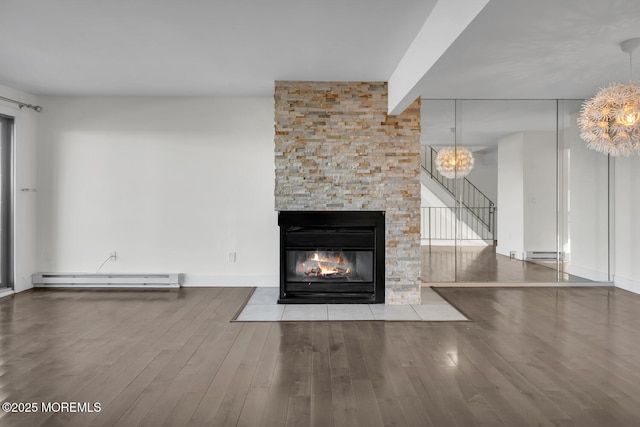 unfurnished living room featuring a fireplace, wood-type flooring, an inviting chandelier, and a baseboard heating unit