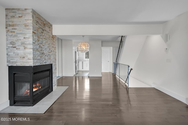 unfurnished living room featuring a chandelier, hardwood / wood-style floors, and a stone fireplace