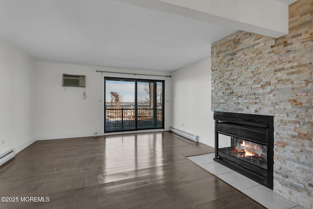 unfurnished living room featuring a wall mounted air conditioner, hardwood / wood-style flooring, a stone fireplace, and baseboard heating