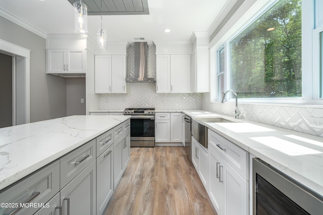 kitchen with beverage cooler, white cabinets, stainless steel gas stove, wall chimney exhaust hood, and crown molding