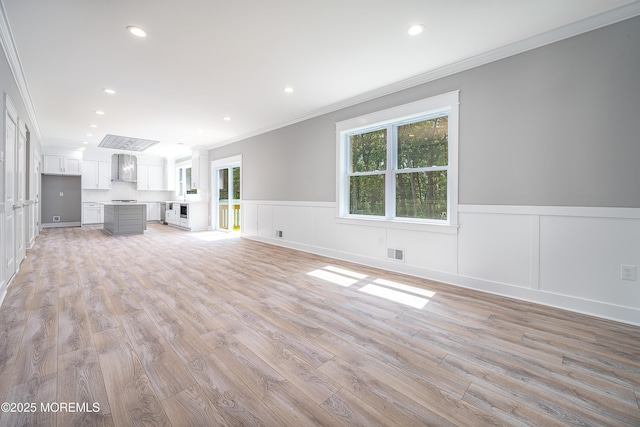 unfurnished living room featuring light wood-type flooring and ornamental molding