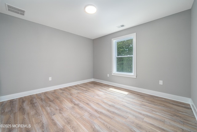 spare room with light wood-style flooring, visible vents, and baseboards