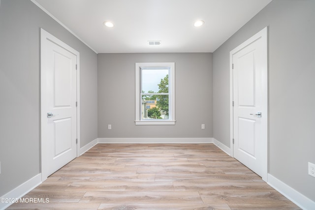 unfurnished room featuring light wood finished floors, baseboards, and visible vents