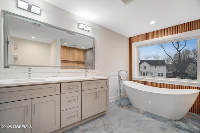 bathroom featuring a soaking tub, marble finish floor, a sink, and double vanity