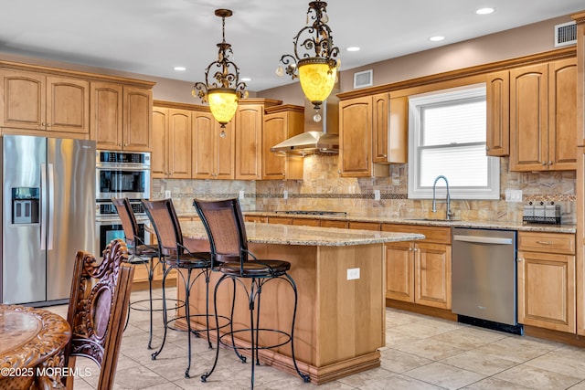 kitchen with stainless steel appliances, sink, wall chimney range hood, pendant lighting, and a center island