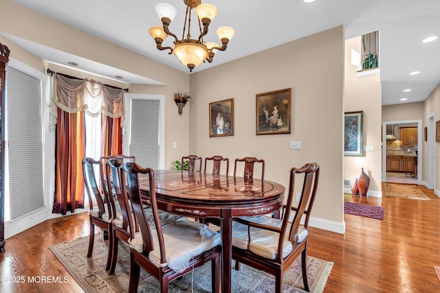 dining area with light wood-type flooring and an inviting chandelier