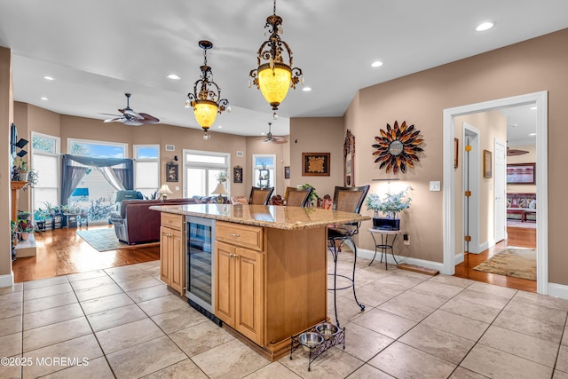 kitchen with a center island, beverage cooler, decorative light fixtures, a breakfast bar, and light tile patterned floors