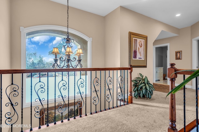 corridor with carpet flooring and an inviting chandelier