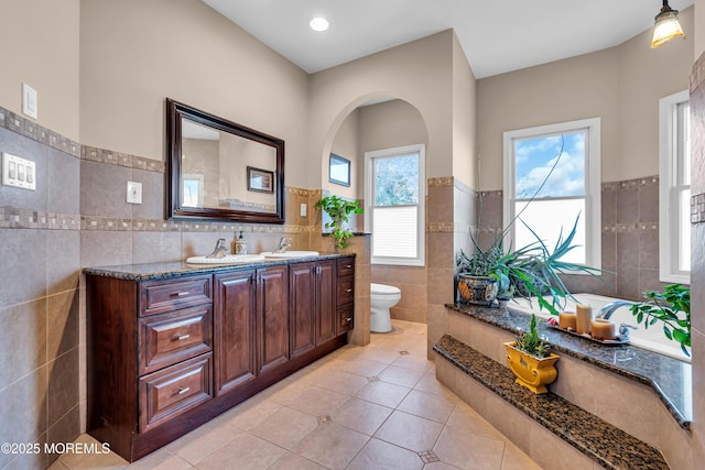 bathroom with tile patterned floors, a wealth of natural light, tile walls, and toilet