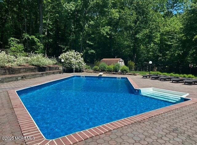 view of swimming pool featuring a diving board and a patio