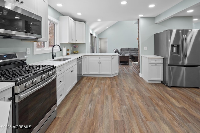 kitchen featuring hardwood / wood-style floors, white cabinets, sink, kitchen peninsula, and stainless steel appliances