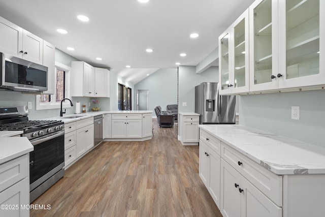 kitchen with sink, light wood-type flooring, appliances with stainless steel finishes, light stone counters, and white cabinetry