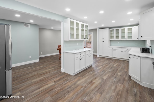 kitchen with dark hardwood / wood-style floors, stainless steel fridge, and white cabinetry