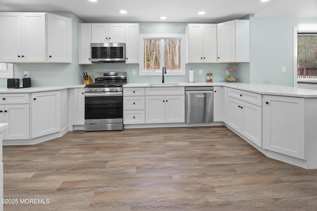 kitchen with sink, white cabinets, stainless steel appliances, and light wood-type flooring