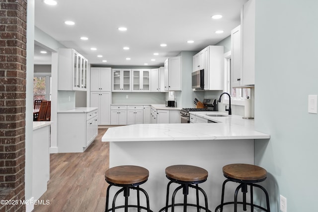 kitchen featuring a kitchen bar, kitchen peninsula, sink, and appliances with stainless steel finishes