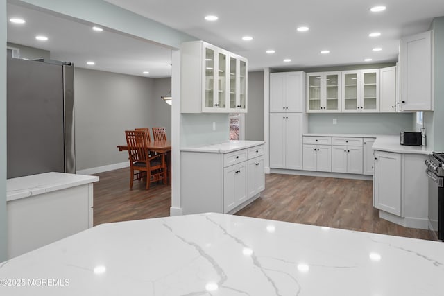 kitchen featuring white cabinets, dark hardwood / wood-style flooring, light stone countertops, and appliances with stainless steel finishes