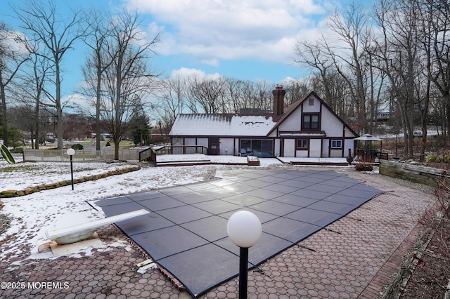 snow covered house featuring a patio area