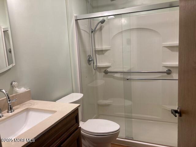 bathroom with a shower with door, vanity, and toilet