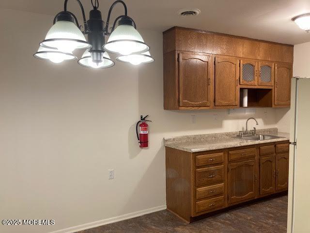 kitchen with white refrigerator, a notable chandelier, hanging light fixtures, and sink