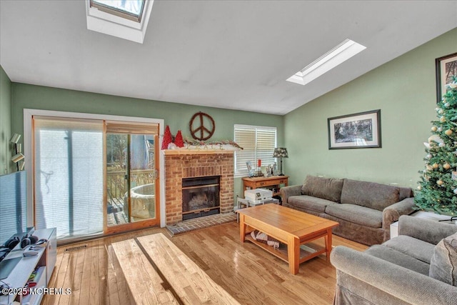 living room featuring lofted ceiling, a fireplace, and light wood-type flooring