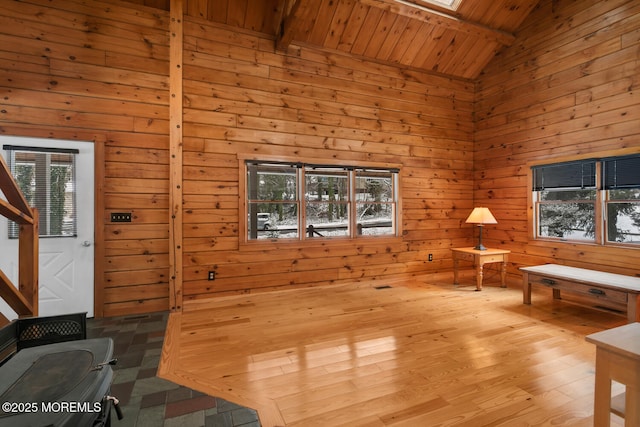 sitting room featuring wood walls, light wood-type flooring, wooden ceiling, and lofted ceiling with skylight