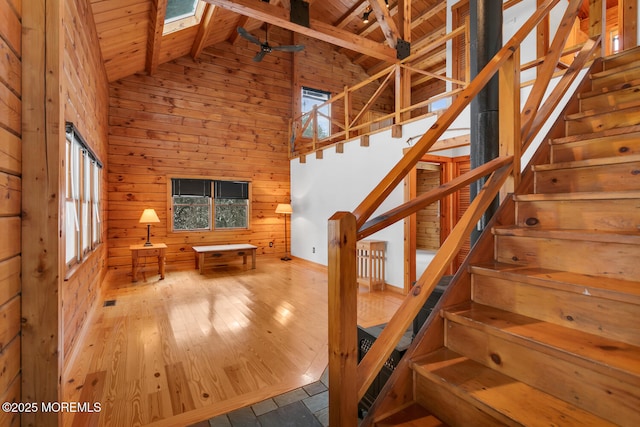 stairs featuring a skylight, wooden ceiling, beamed ceiling, high vaulted ceiling, and wooden walls