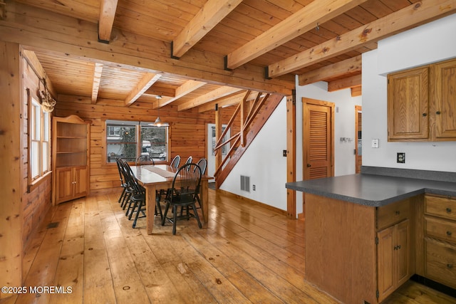 dining area featuring beamed ceiling, light wood-type flooring, wood ceiling, and wood walls